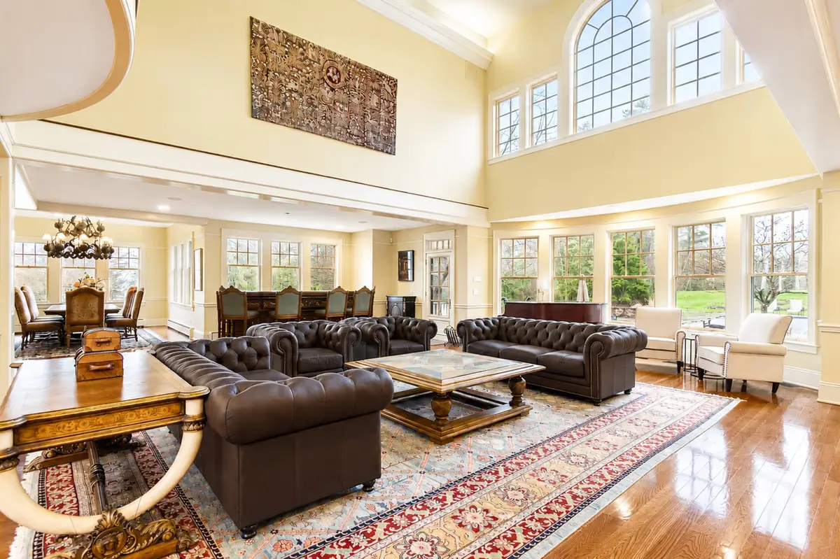 Wide-angle interior view of the magnificent Great Room featuring soaring timber trusses, a massive stone fireplace, two Chesterfield leather sofas, and a grand piano.
